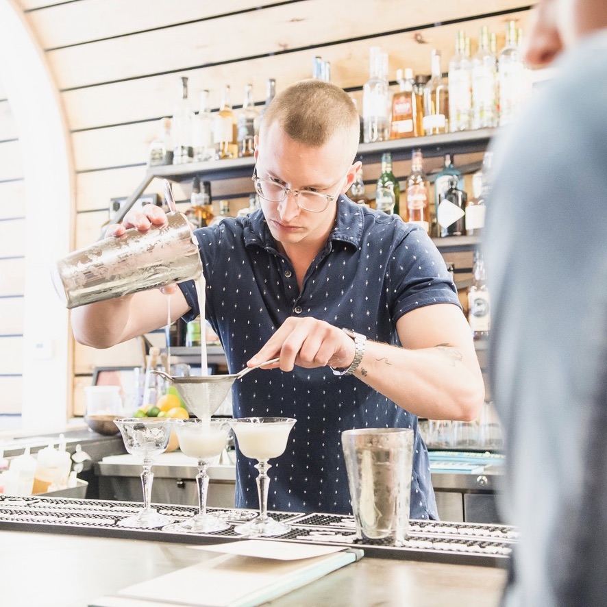 Harry showing others how to pour a cocktail expertly behind a bar